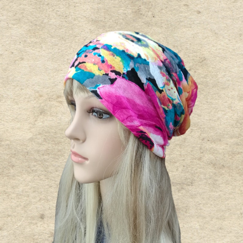 May include: A colorful floral patterned beanie hat with pink, blue, yellow, and white accents. The hat is made of a soft, stretchy fabric and is perfect for casual wear.