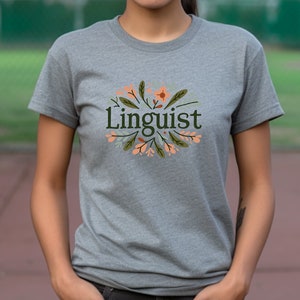 May include: A gray t-shirt with a floral design and the word "Linguist" in green text.