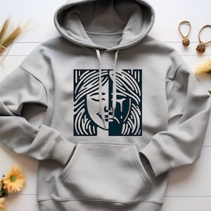 May include: A gray hoodie with a black and white graphic print of a woman's face. The face is split in half, with one side smiling and the other side crying.