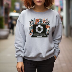 May include: A gray sweatshirt with a floral design featuring a laptop with a white flower on the screen.