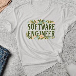 Puede incluir: Camiseta blanca con un diseño floral verde y el texto "SOFTWARE ENGINEER" en letras verdes.