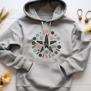 May include: A gray hoodie with a floral design featuring a black starfish in the center. The flowers are in shades of pink, blue, and green.