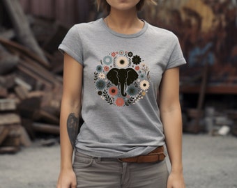 Puede incluir: Una camiseta gris con un diseño floral que presenta una silueta de elefante en el centro. Las flores son en tonos de azul, rosa y amarillo.