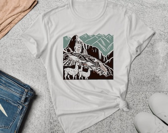 Puede incluir: Camiseta blanca con un estampado gráfico de un paisaje de montaña con llamas. El paisaje está en tonos marrones, verdes y azules.