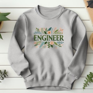 Puede incluir: Sudadera gris con un diseño floral y la palabra "ENGINEER" en letras verdes.