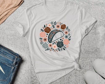 May include: White t-shirt with a floral design featuring a taco in the center. The flowers are in shades of pink, red, and blue.