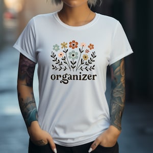 May include: White t-shirt with a floral design and the word "organizer" printed in brown.