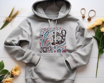 May include: A gray hoodie with a colorful floral design featuring a teapot and a cup. The design is centered on the front of the hoodie.