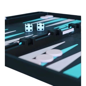 Könnte beinhalten: Ein Backgammon-Brett mit schwarzer Oberfläche, weißen und türkisfarbenen dreieckigen Markierungen und zwei weißen Würfeln mit den Zahlen 4 und 2. Das Spielbrett enthält auch weiße und rosa Spielsteine.