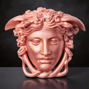 A rose gold Medusa head sculpture with snakes for hair and under the chin, against a dark background.