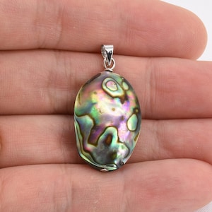 May include: A silver pendant featuring a green, iridescent abalone shell with a natural pattern. The shell is oval shaped and has a silver bail.
