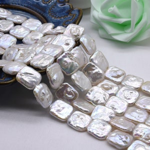 Puede incluir: Una hebra de cuentas de perlas de agua dulce barrocas blancas. Las perlas son de forma cuadrada y tienen un brillo iridiscente.