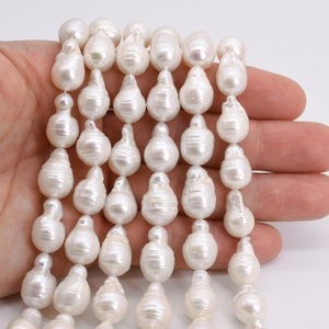 May include: A strand of white baroque pearls, each pearl is a unique, irregular shape. The pearls are strung on a white thread and are approximately 10mm in size.