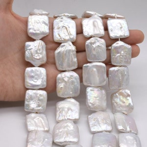 May include: Strand of white, square-shaped pearl beads. The pearls have a lustrous, iridescent sheen and irregular surfaces. The beads are strung together, showcasing their unique, natural forms. Ideal for jewelry making.