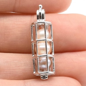 May include: Silver cage pendant with three white pearls inside. The cage is open at the top and bottom, and the pearls are visible through the bars.