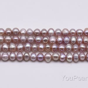 May include: A strand of lavender freshwater pearls. The pearls are round and have a slight iridescent sheen.