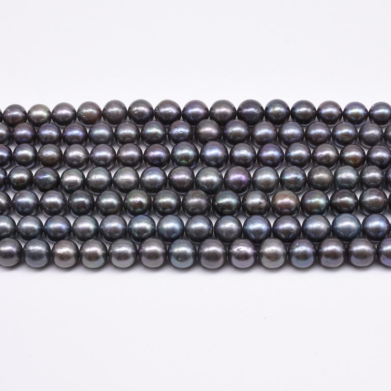 May include: A strand of black freshwater pearls. The pearls are round and have a slight iridescent sheen.
