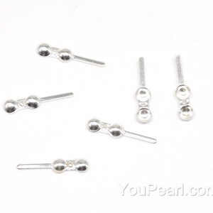 May include: Five silver-toned metal bead caps with a loop on one end and two beads on the other end. The bead caps are designed for jewelry making.