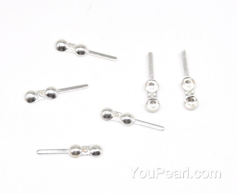 May include: Five silver-toned metal bead caps with a loop on one end and two beads on the other end. The bead caps are designed for jewelry making.
