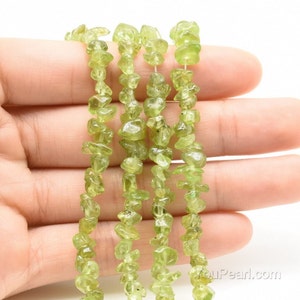 May include: A strand of light green peridot chip beads. The beads are irregular in shape and have a natural, rough texture.