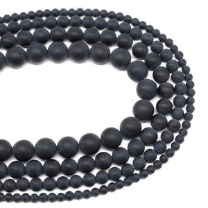 May include: A strand of black matte round beads of varying sizes. The beads are strung together on a clear thread.