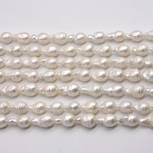May include: A strand of white baroque pearls, with a slightly irregular shape, arranged in rows on a white background.