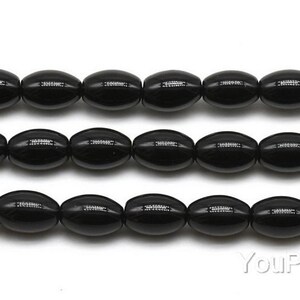 May include: A strand of black oval-shaped beads. The beads are smooth and glossy.