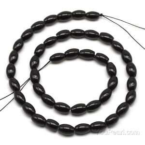 May include: A strand of black oval-shaped beads, approximately 10mm in size, strung on a black thread. The beads are made of polished black onyx.