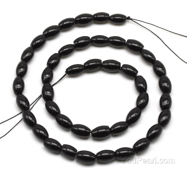 May include: A strand of black oval-shaped beads, approximately 10mm in size, strung on a black thread. The beads are made of polished black onyx.