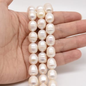 Puede incluir: Una hebra de perlas de agua dulce blancas con forma barroca. Las perlas son lisas y lustrosas, con una forma ligeramente irregular.