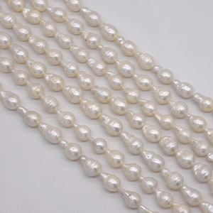 May include: A strand of white freshwater pearls with a baroque shape. The pearls are strung on a white thread and are arranged in a staggered pattern.