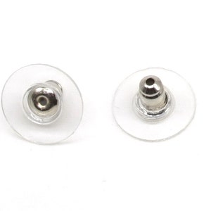 May include: Two clear plastic earring backs with a silver metal post. The backs are designed to hold earrings in place.