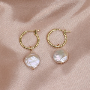 May include: A pair of gold hoop earrings with a single pearl dangling from each hoop. The pearls are off-white and have an irregular shape.