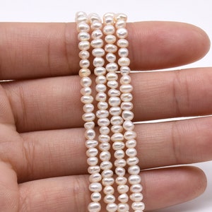 May include: A strand of white freshwater pearls, strung on a thin thread. The pearls are small and round, with a smooth, glossy finish.