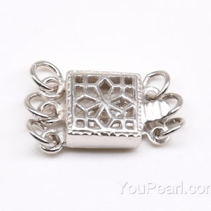 Puede incluir: Cierre de metal plateado con un diseño decorativo calado. El cierre tiene cuatro bucles para sujetar un collar o una pulsera.