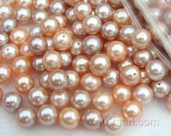 May include: A collection of lustrous, round pearls in shades of peach, pink, and silver. Each pearl has a smooth, reflective surface and a small hole. The pearls are scattered, suggesting they are loose or in a container.