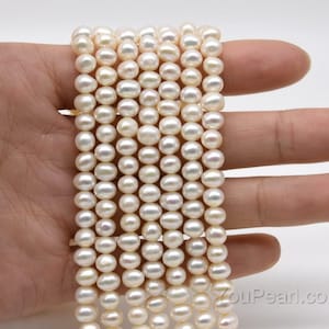 Puede incluir: Una hebra de perlas de agua dulce blancas, de aproximadamente 6-7 mm de tamaño, con una forma redonda y lisa. Las perlas están enhebradas en un hilo blanco y están listas para ser utilizadas en la elaboración de joyas.