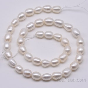 May include: A strand of white oval freshwater pearls, approximately 8mm in size, strung on a white thread. The pearls are arranged in a loose, flowing pattern, creating a delicate and elegant look.