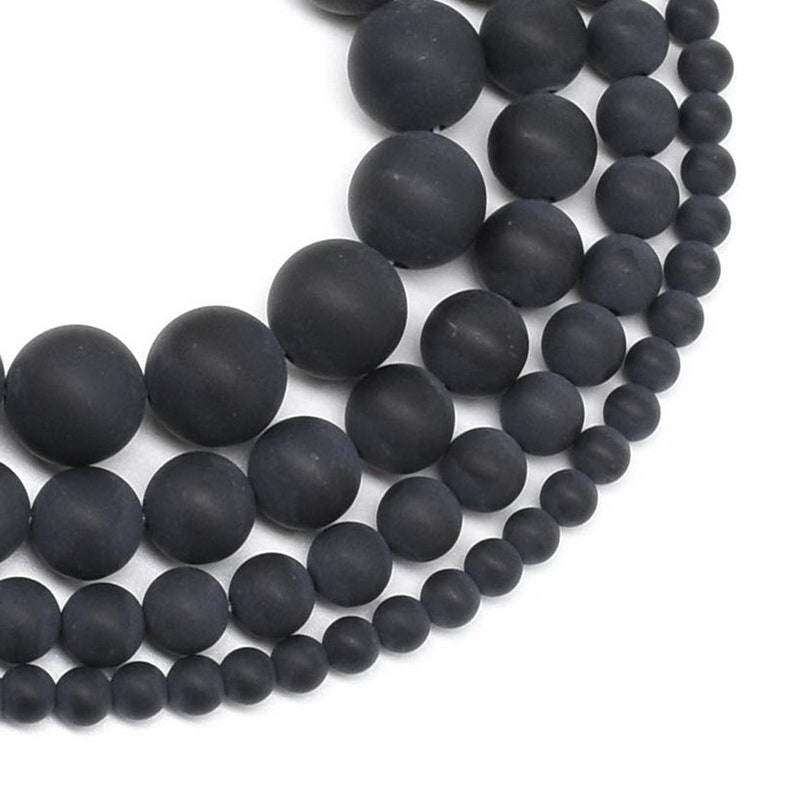 May include: A strand of black agate beads in various sizes, ranging from small to large. The beads are round and smooth, with a matte finish.
