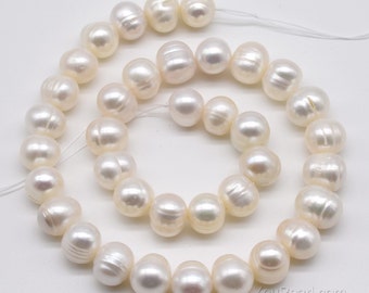 May include: A strand of white freshwater pearls, with a smooth, round shape. The pearls are strung on a white thread and are arranged in a circular pattern.