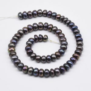 Puede incluir: Una hebra de perlas negras iridiscentes, con una hebra de perlas más pequeña enroscada alrededor. Las perlas son redondas y tienen un acabado liso y brillante.