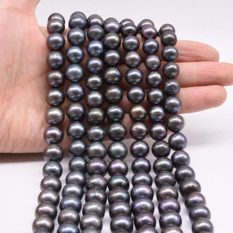 May include: A strand of black freshwater pearls with a slight iridescent sheen. The pearls are round and smooth, and they are strung on a clear thread.