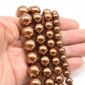 May include: A strand of brown pearl beads in various sizes. The beads are round and have a glossy finish.
