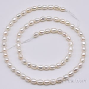 May include: A strand of white freshwater pearls, with a smooth, oval shape. The pearls are strung on a white thread and are approximately 6-7mm in size.