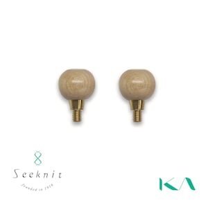May include: Two wooden ball-shaped knitting needle stoppers with brass screw bases. The stoppers are light brown and have a smooth, rounded design. The image is set against a white background. The Seeknit logo is in the lower left corner.