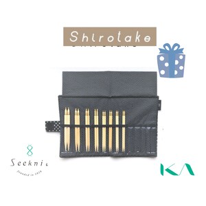 May include: A set of light-colored wooden knitting needles stored in a black fabric case with a white polka dot pattern. The case features the text Shirotake, Seeknit, and KA. A blue gift box icon with white polka dots is positioned to the right.