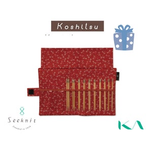 Könnte beinhalten: Ein rotes Stricknadel-Etui aus Stoff mit einem Libellenmuster, geöffnet, um ein Set aus Stricknadeln aus Bambus zu zeigen. Das Etui ist mit "Koshitsu" beschriftet und enthält das "Seeknit"-Logo.