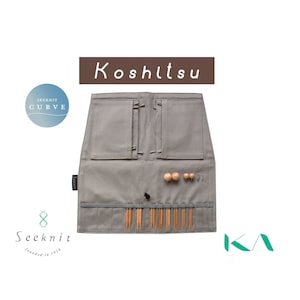 May include: A gray canvas roll-up case with the word "Koshitsu" printed on the front. The case has two pockets and a zippered compartment. The case is filled with knitting needles and other accessories. The case is labeled "Seeknit" and "founded in 1916".