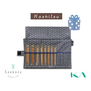 May include: A set of wooden knitting needles stored in a navy blue fabric case with a white geometric star pattern. The case features a flap, a velcro closure, and a blue strap to hold the needles. Text includes Koshitsu, Seeknit, and KA.