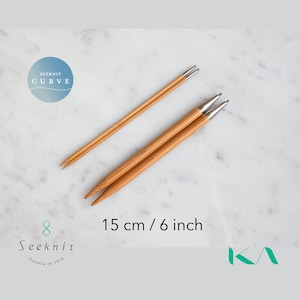 May include: Two pairs of Seeknit Curve knitting needles. The needles are made of light brown bamboo with silver tips. The image includes the text "15 cm / 6 inch". The Seeknit logo is also visible.